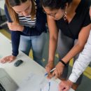 two women studying charts on a desk